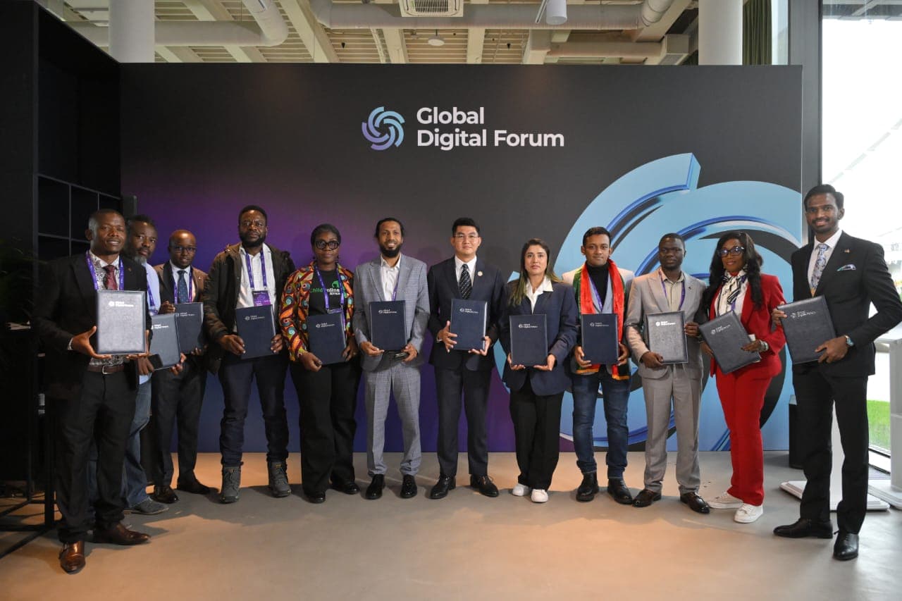 Forum delegates holding signed partnership agreements in front of the Global Digital Forum backdrop